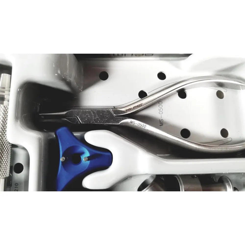 Silver surgical forceps with engraved markings resting in white tray from acumed modular hand system set missing piece