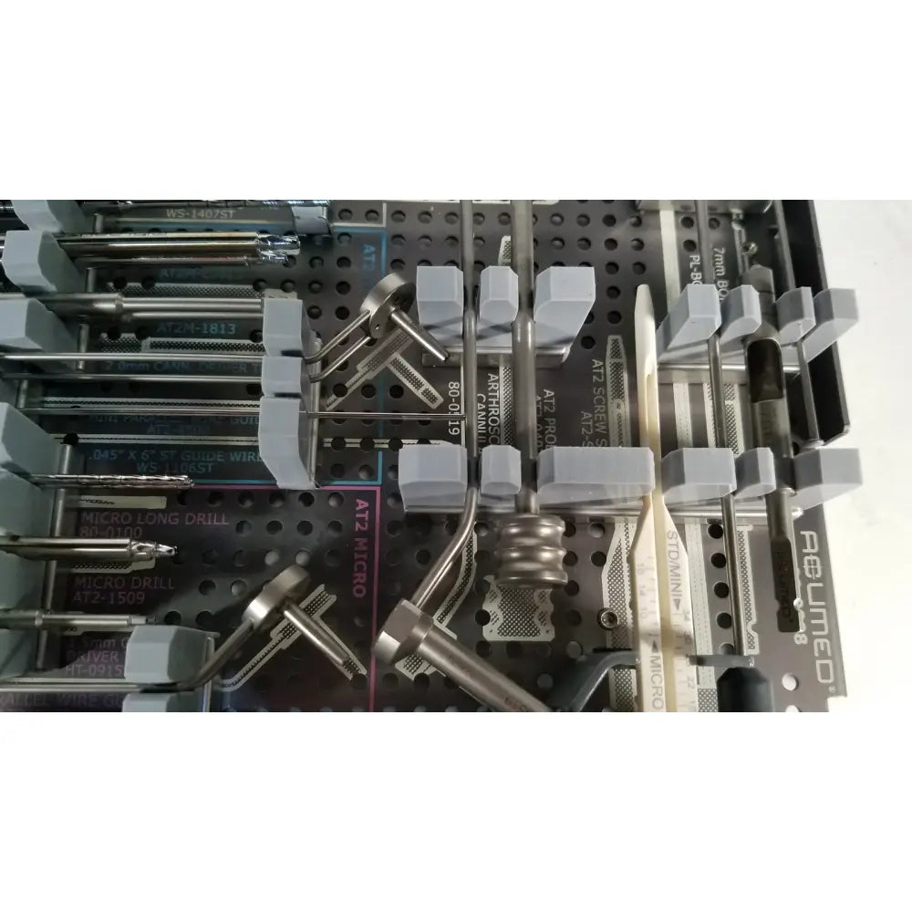 Gray plastic and metallic surgical instruments in a perforated tray for acutrak 2 headless compression screw system reuse medical kit