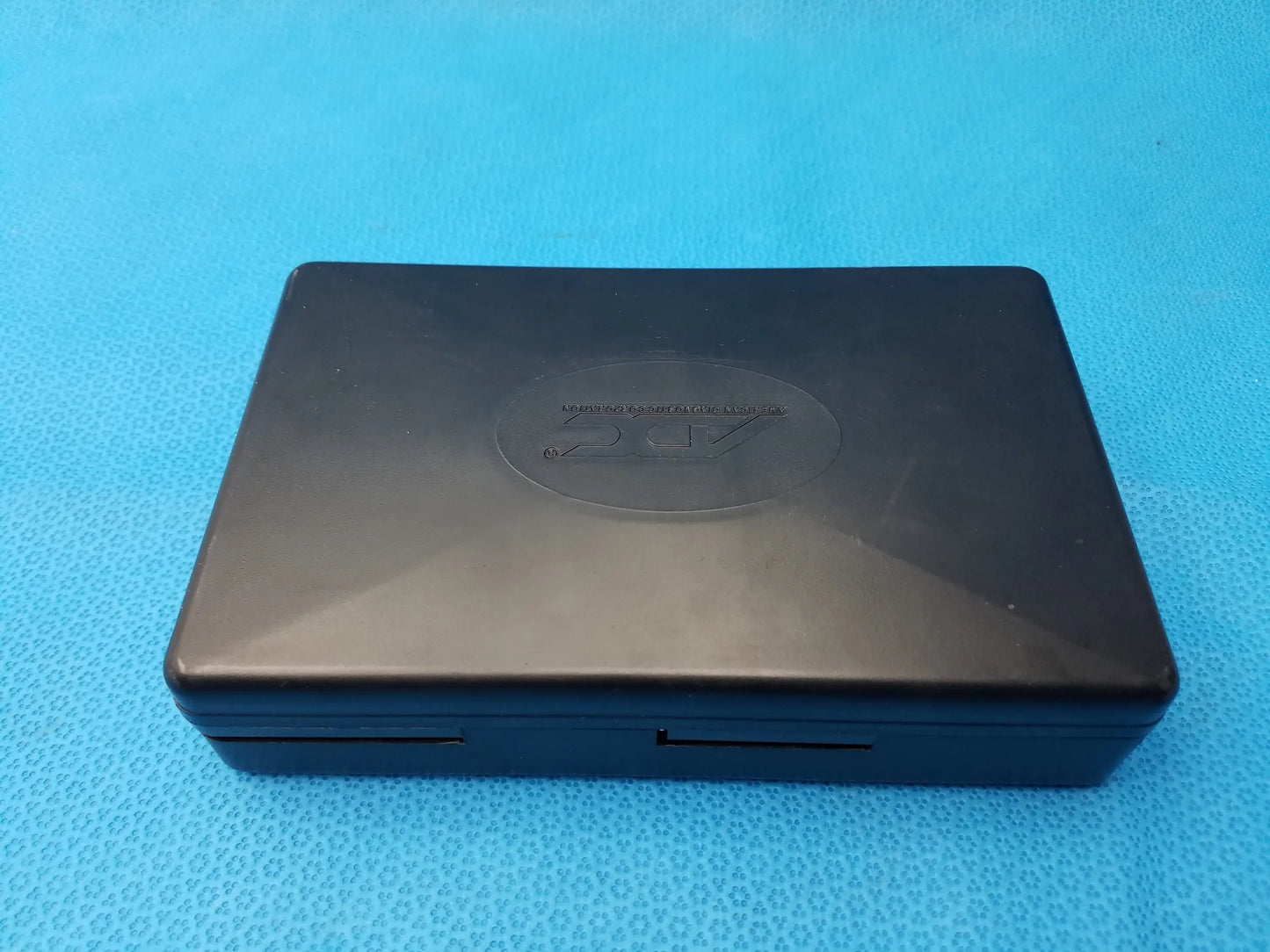 Black plastic nintendo ds with matte finish and ds logo embossed, shown with adc diagnostix pocket diagnostic set case