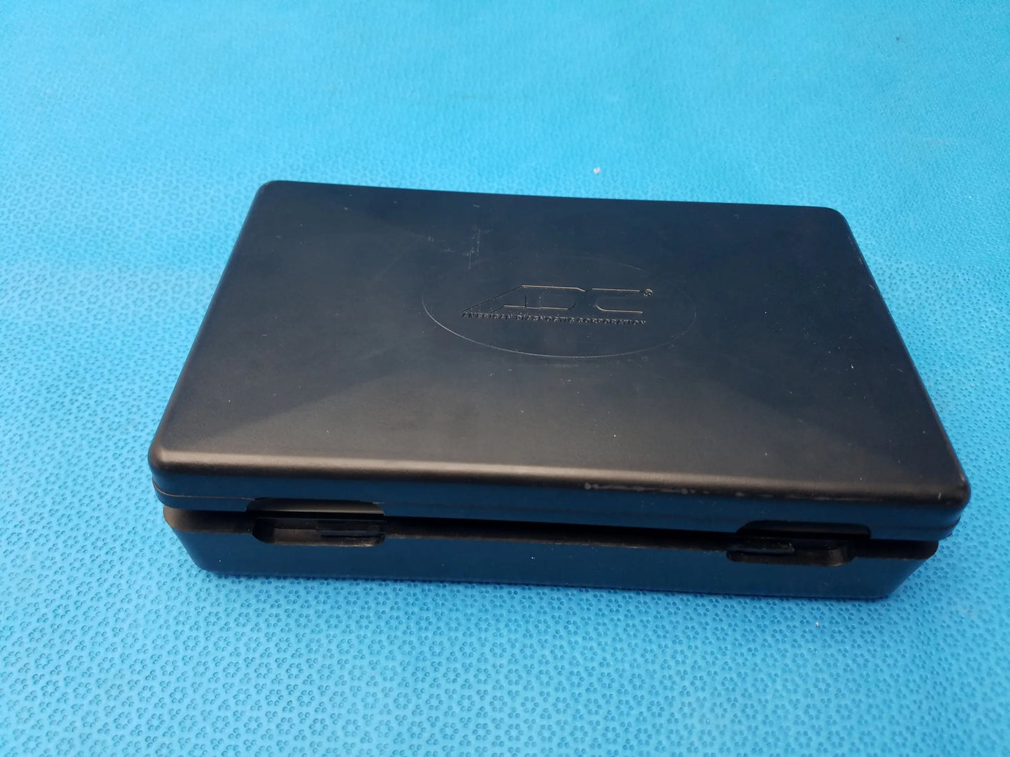 Black nintendo ds handheld console with matte plastic finish and embossed ds logo shown with adc diagnostix pocket diagnostic set case