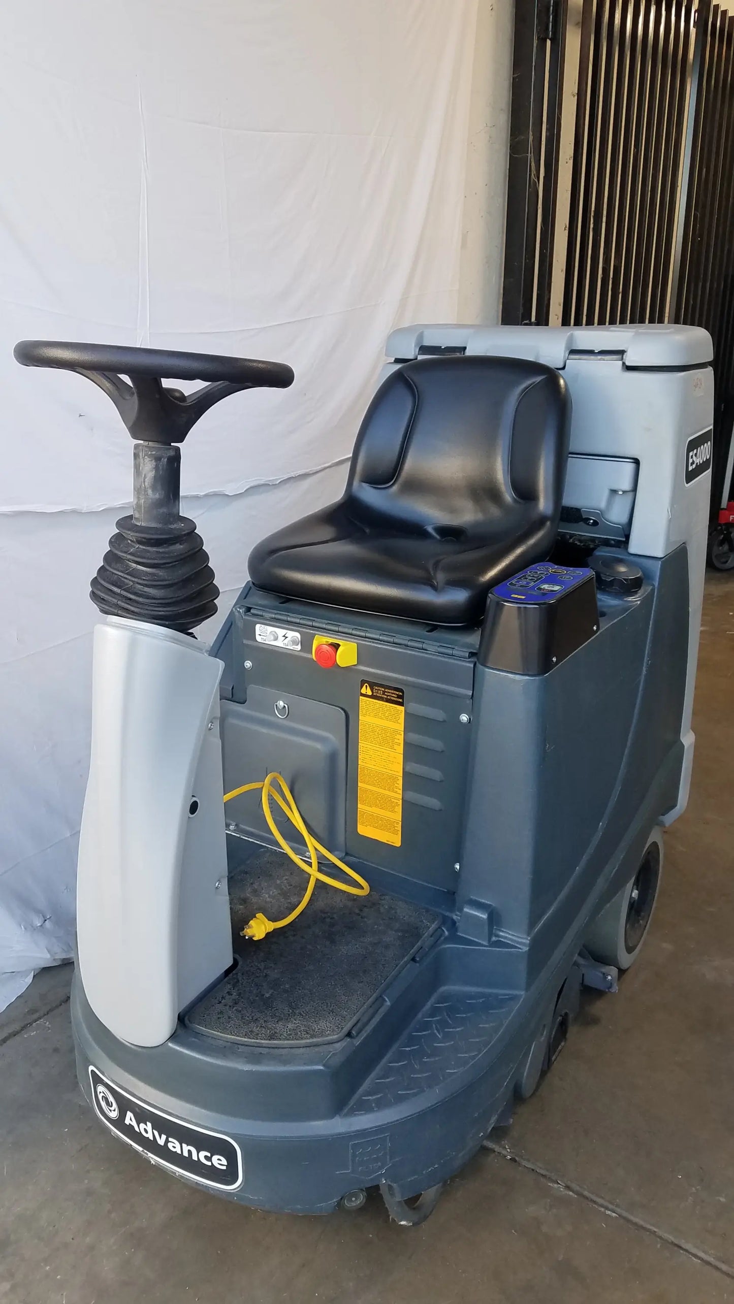 Gray and black advance es4000 ride on carpet cleaner extractor with steering wheel seat and yellow power cord