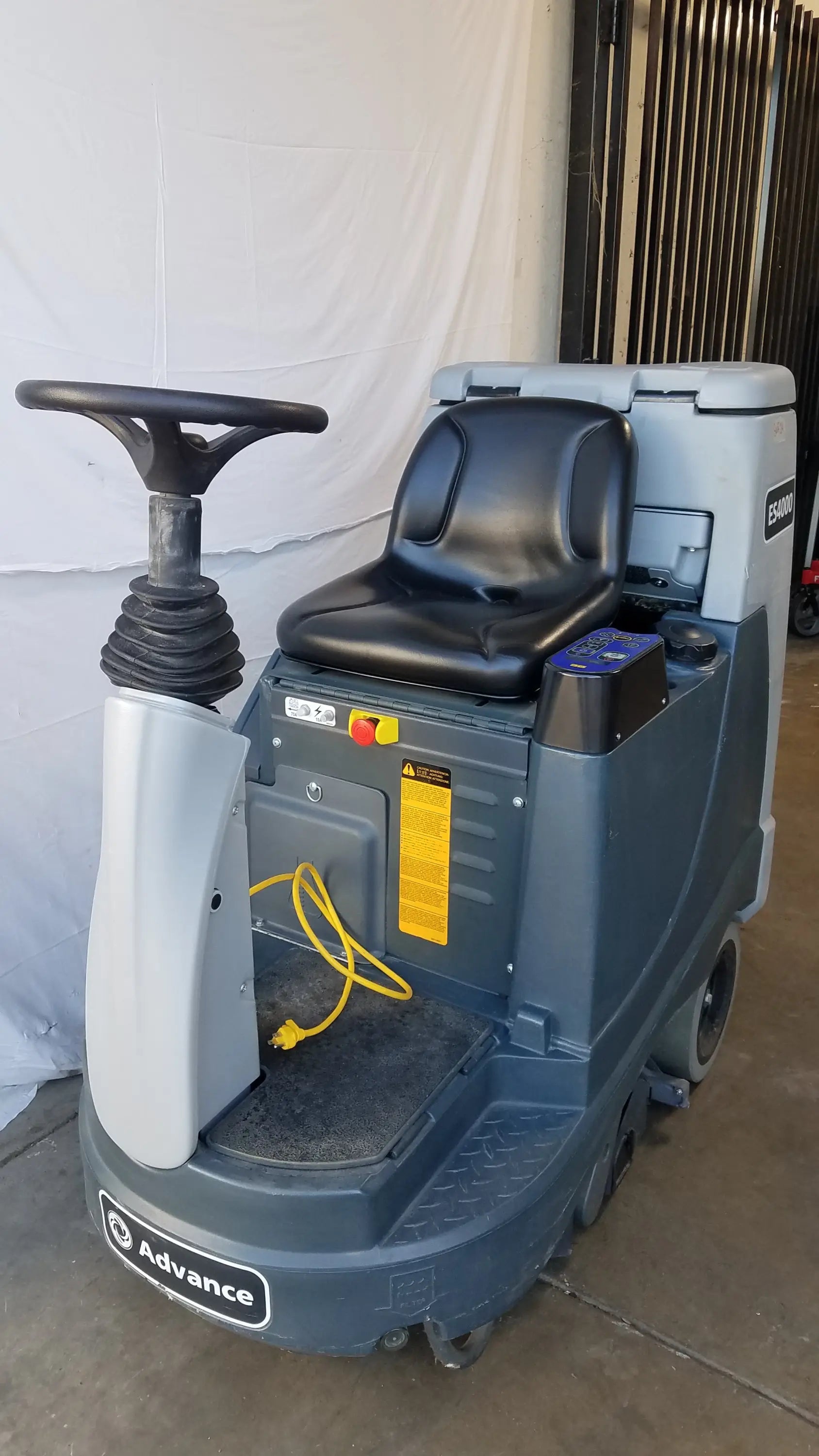 Gray and black advance es4000 ride on carpet cleaner extractor with steering wheel seat and yellow power cord