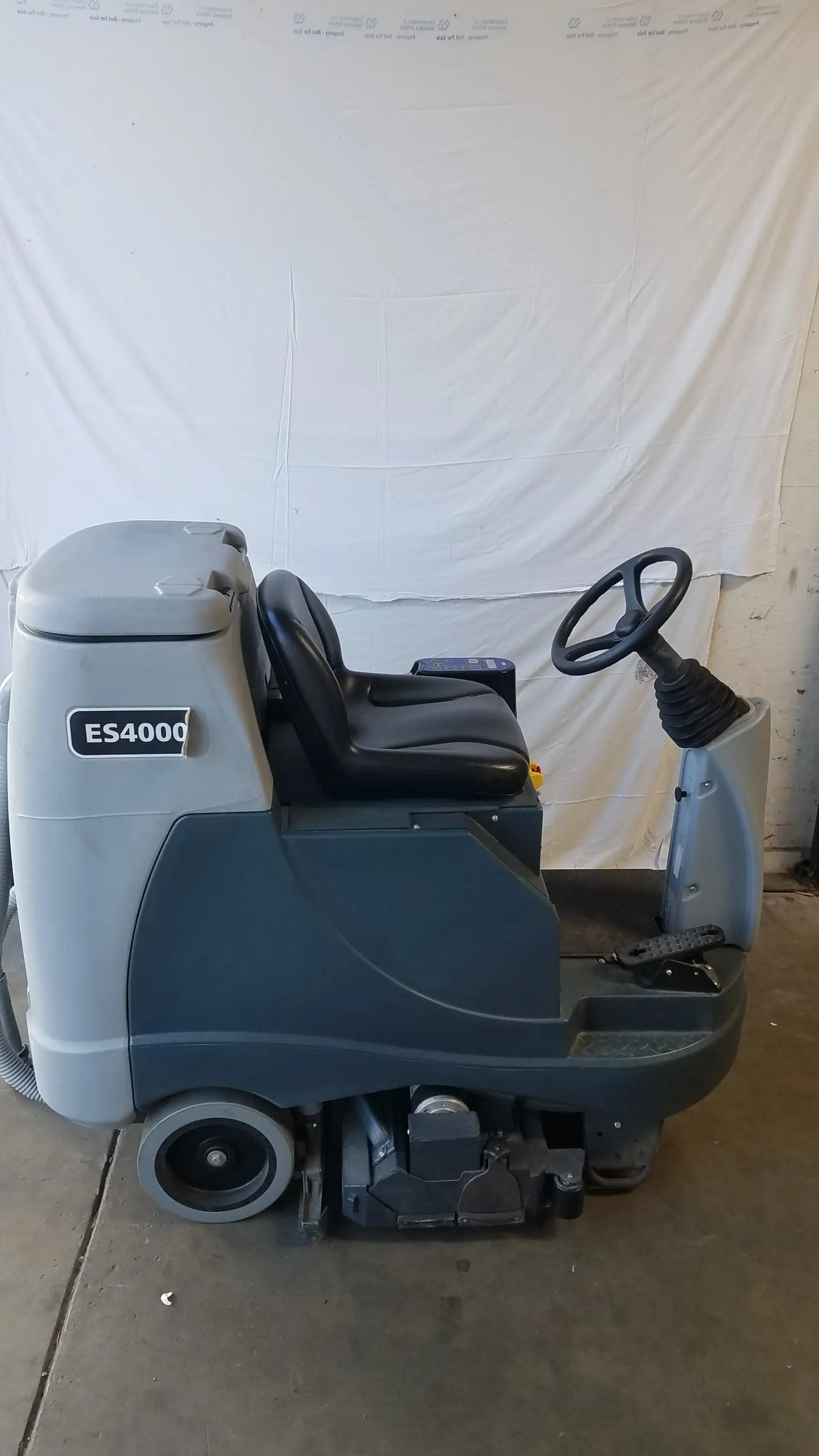Gray and black Advance ES4000 ride on carpet cleaner extractor with driver seat and front cleaning brushes for wet dry use