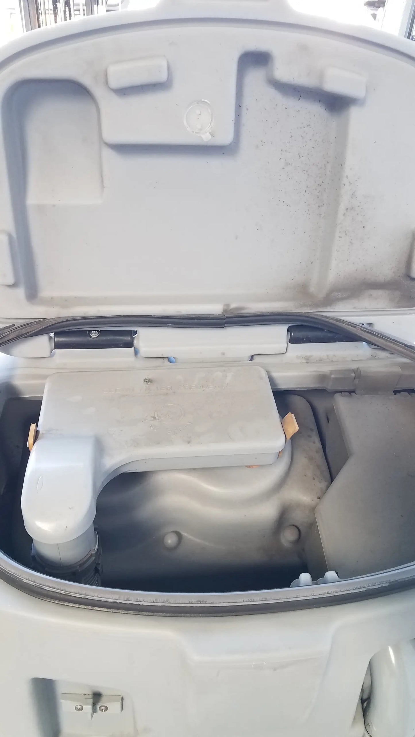 Gray plastic engine cover with molded contours and circular emblem on advance ES4000 ride on carpet cleaner extractor