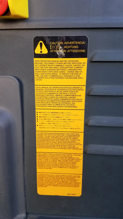 Yellow warning label with caution symbol on gray metallic surface of advance ES4000 ride on carpet cleaner extractor