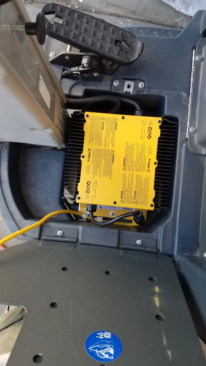 Yellow rectangular battery with black wiring and quik branding inside dark gray enclosure of advance es4000 carpet cleaner extractor