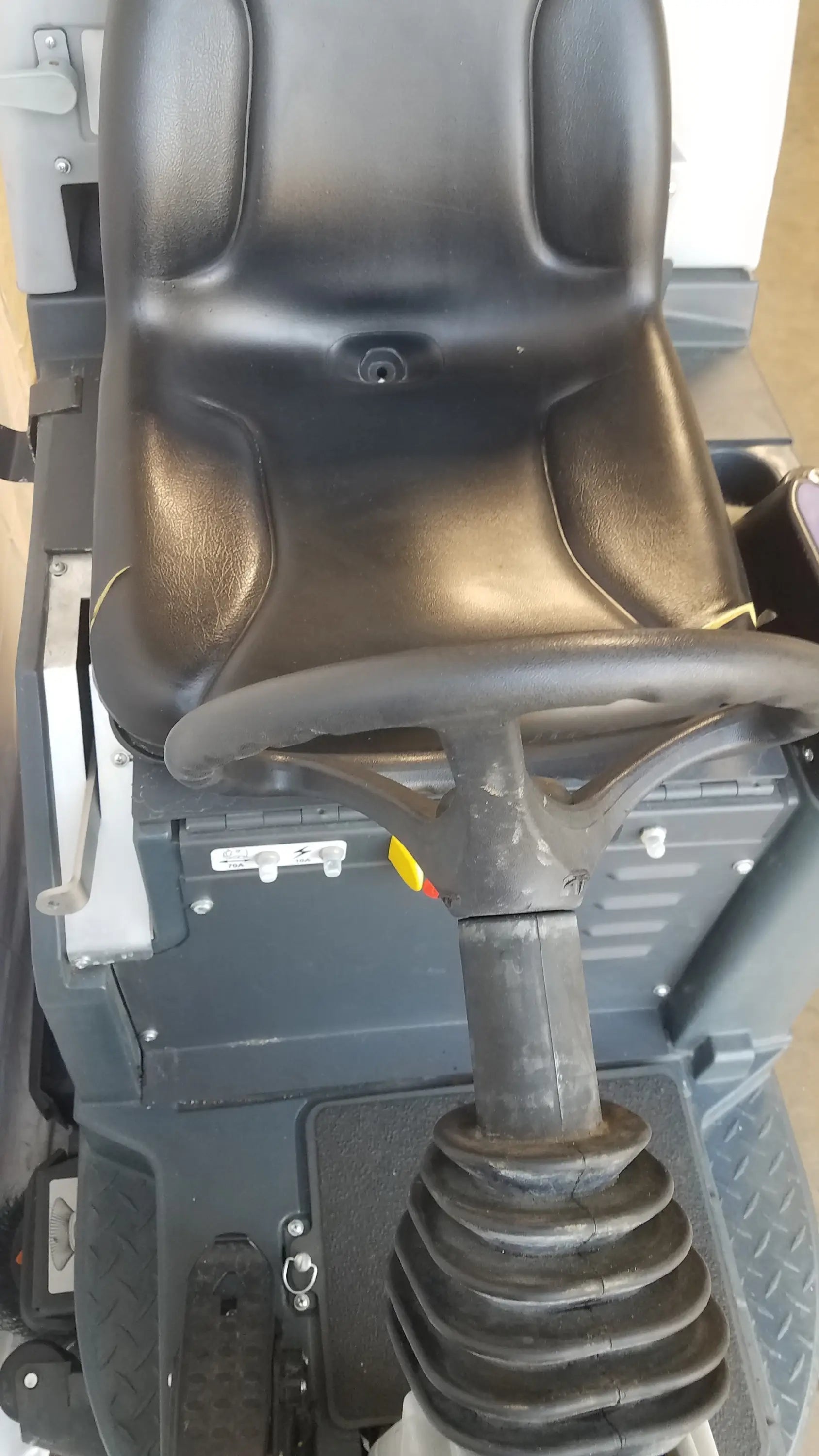 Black leather-like seat with integrated headrest and steering wheel on advance ride on carpet cleaner extractor utility vehicle