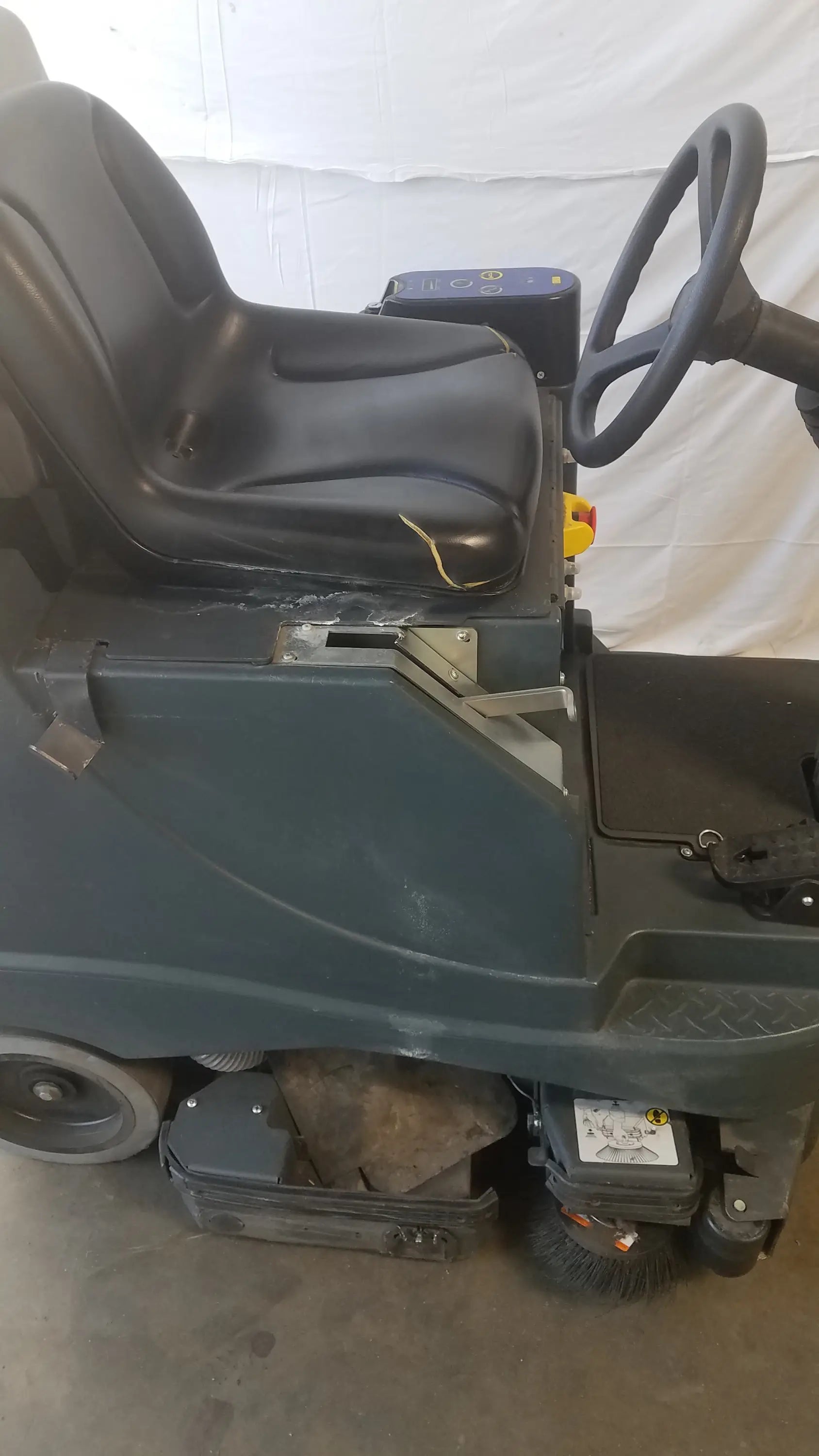 Advance ride on carpet cleaner extractor with black leather driver seat and yellow stitching on green commercial floor cleaning machine