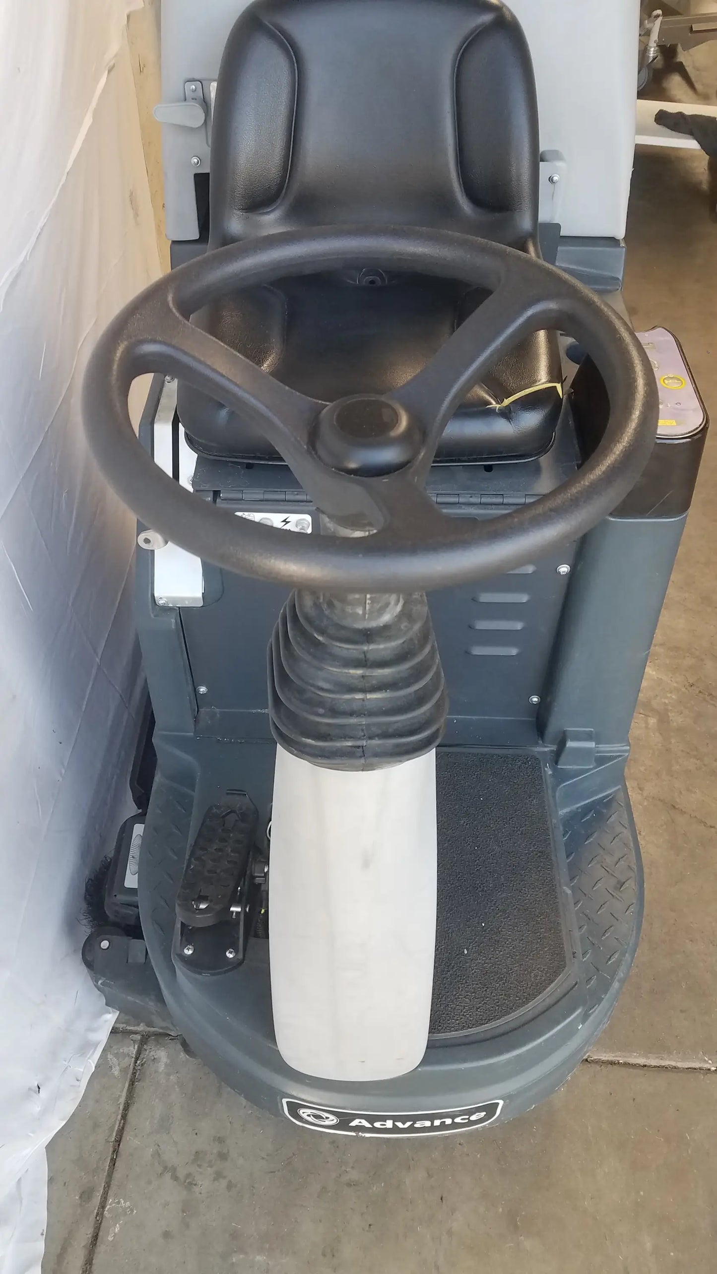 Black three-spoke steering wheel on gray advance ride on carpet cleaner extractor for wet dry vacuum cleaning