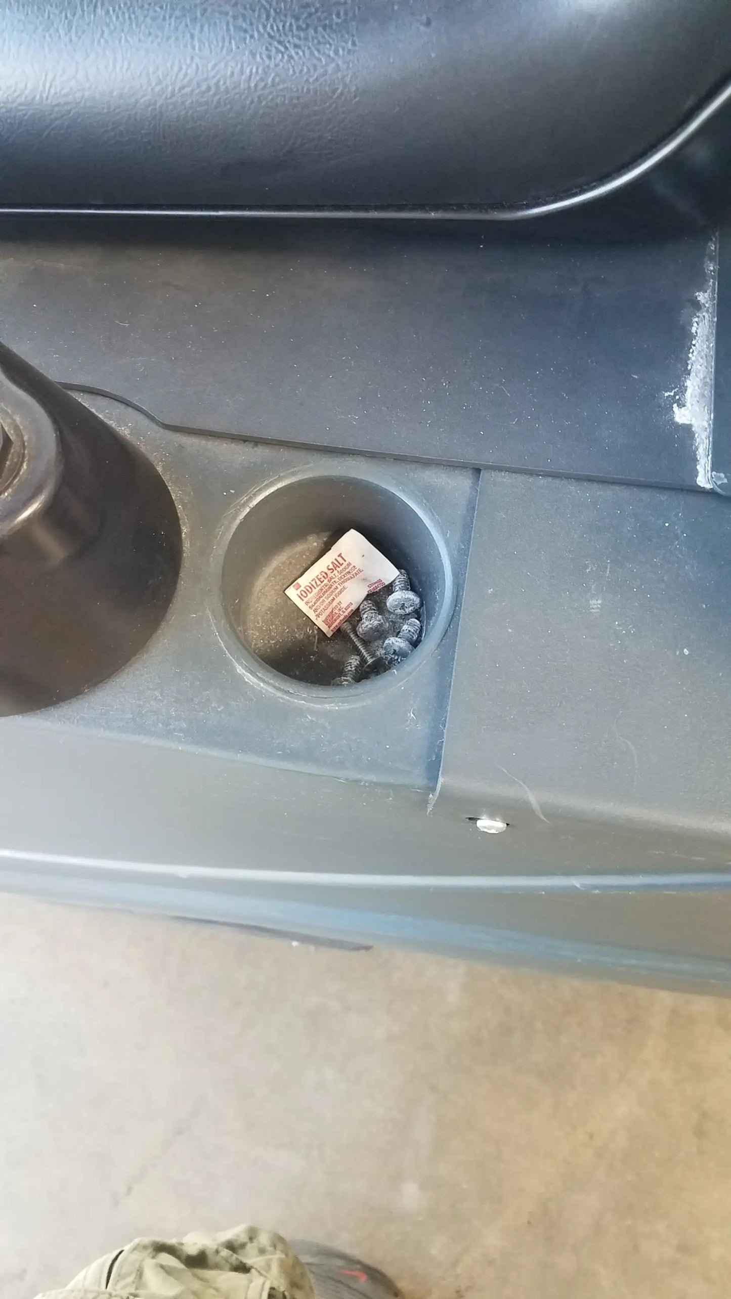 A red and white paper packet in a dark gray plastic car cup holder with advance ride on carpet cleaner extractor wet dry vacuum