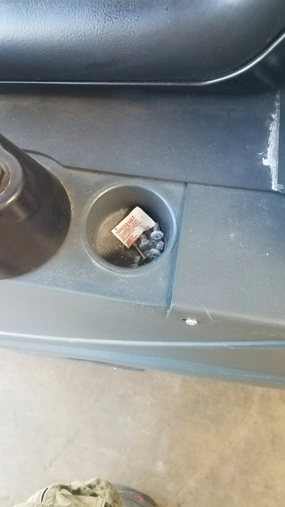 A red and white paper packet in a dark gray plastic car cup holder with advance ride on carpet cleaner extractor wet dry vacuum