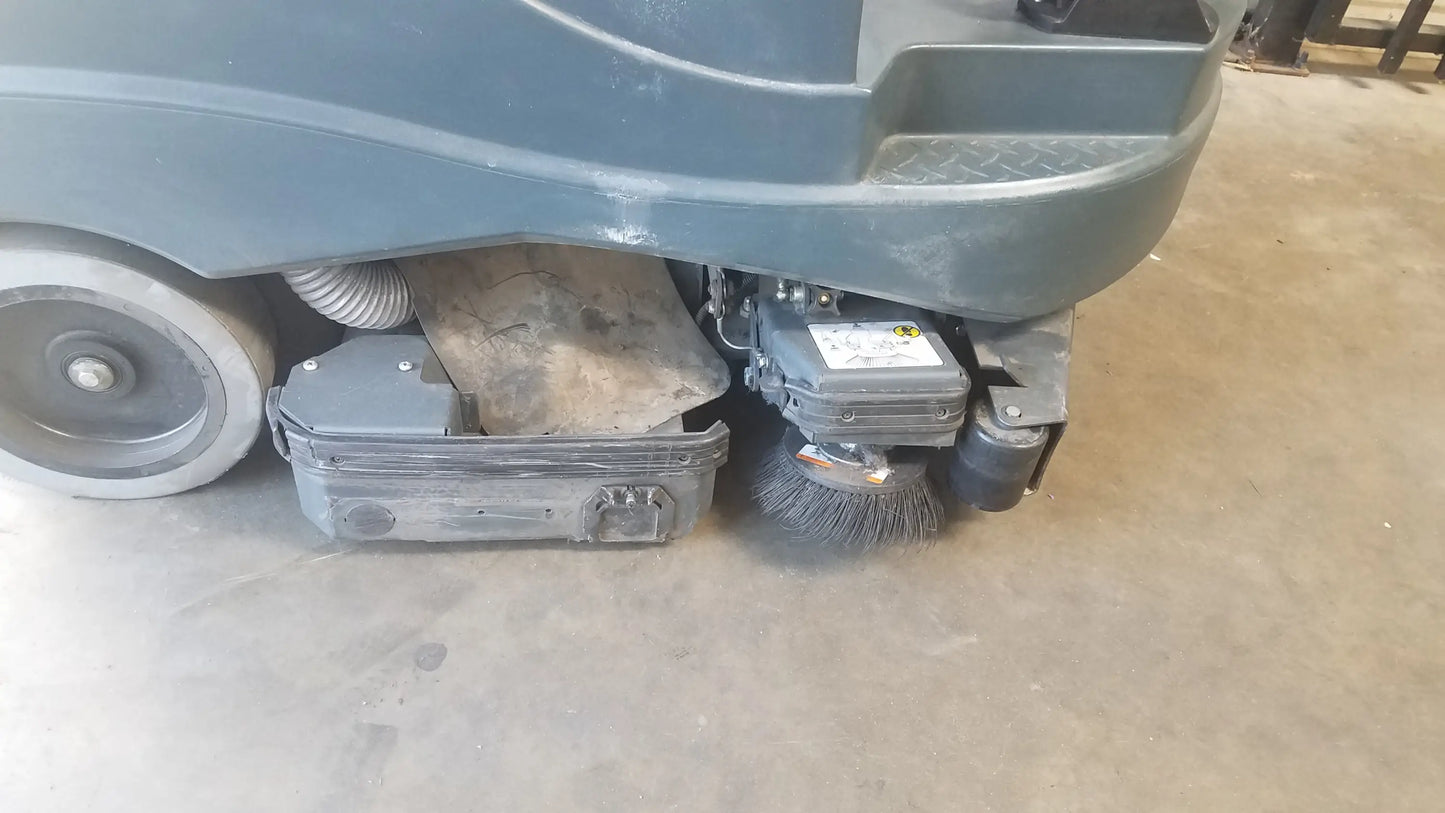 Gray advance ride on carpet cleaner extractor showing industrial floor sweeper brush and mechanical components underneath