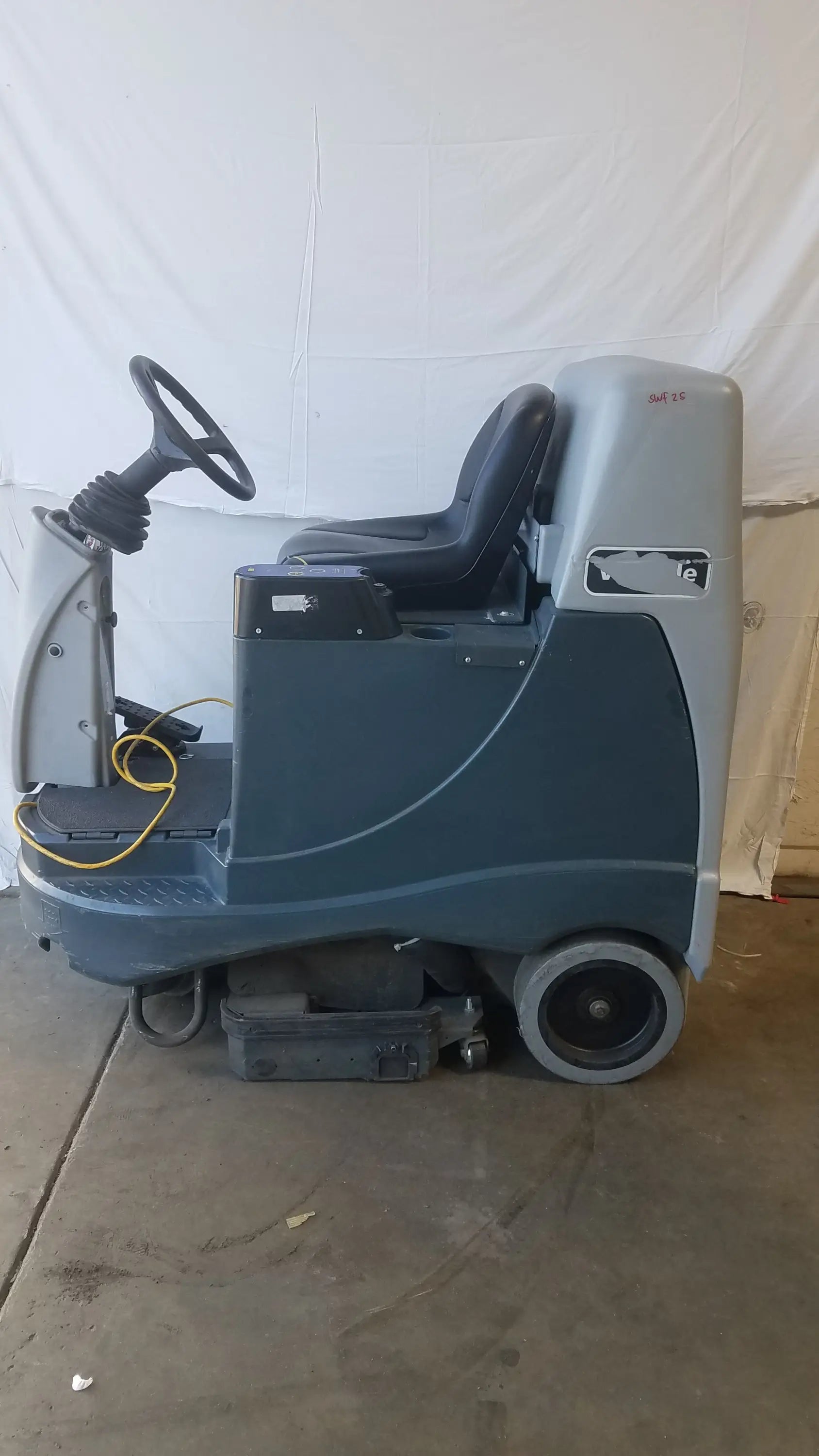 Gray and black advance ride on carpet cleaner extractor with steering wheel operator seat and visible cleaning brushes