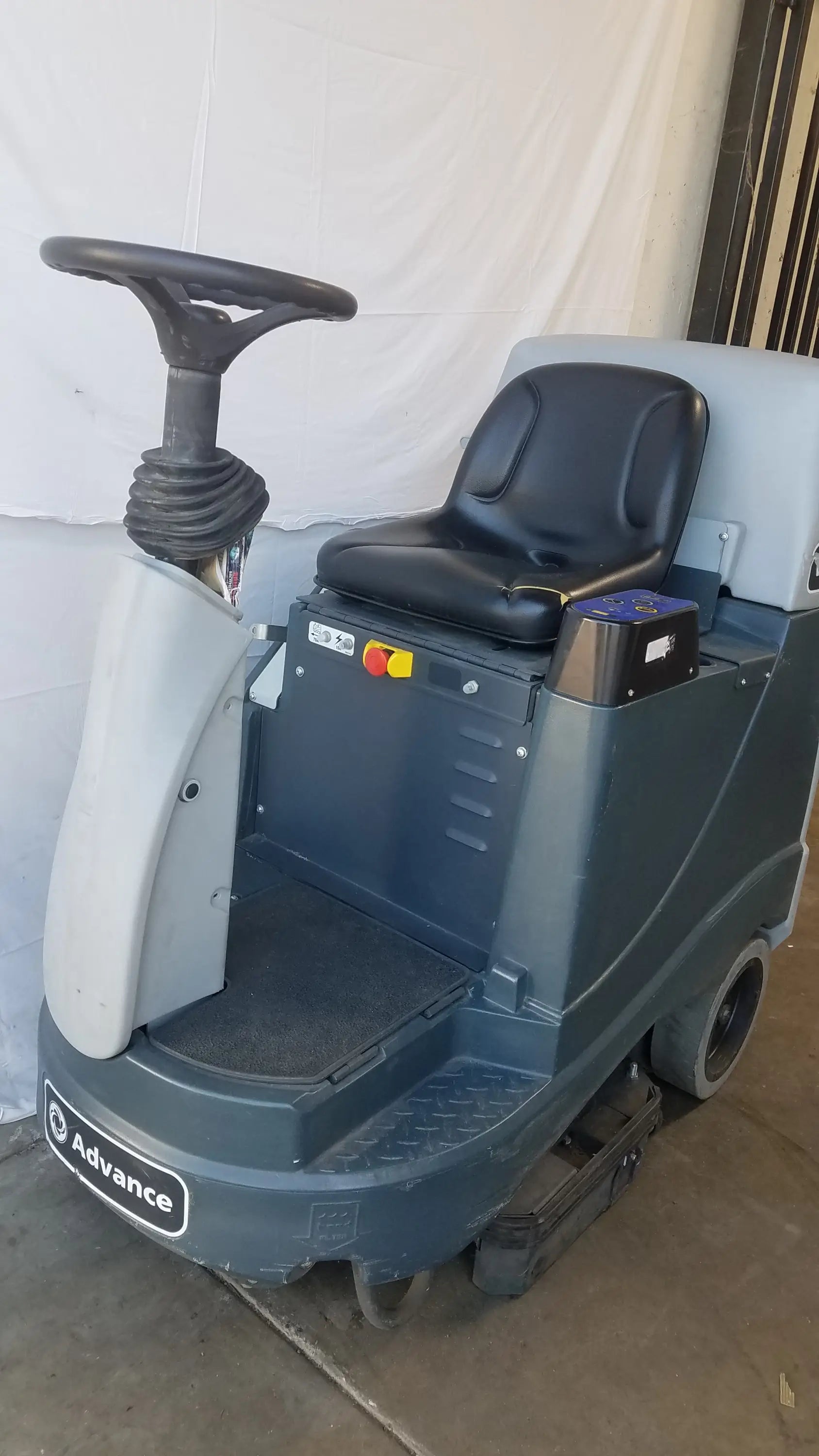 Gray and black Advance ride on carpet cleaner extractor with padded seat, steering wheel, and scrubbing brushes for commercial use