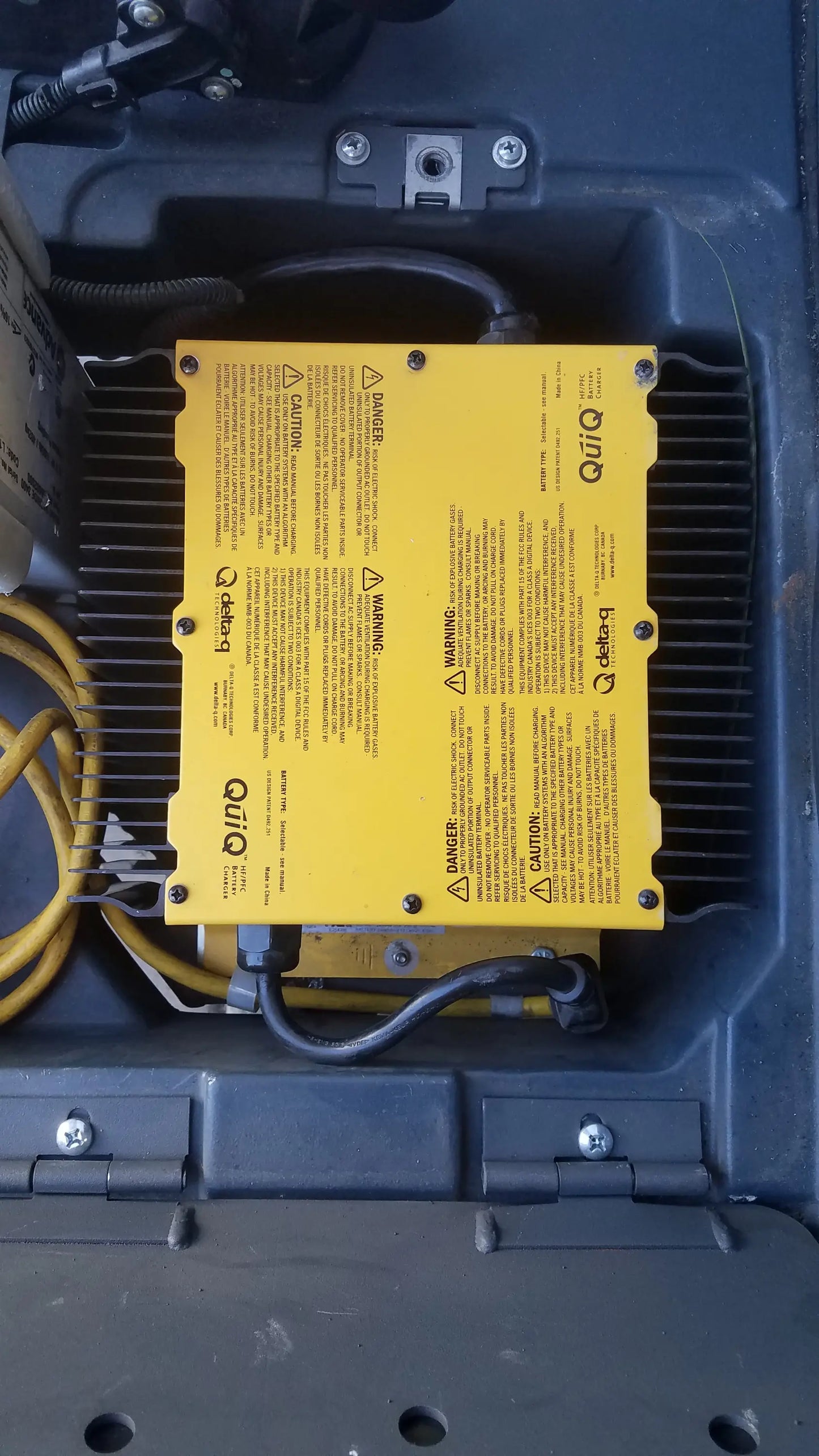 Yellow rectangular electronic control module with black wiring and safety labels on the back of advance ride on carpet cleaner extractor
