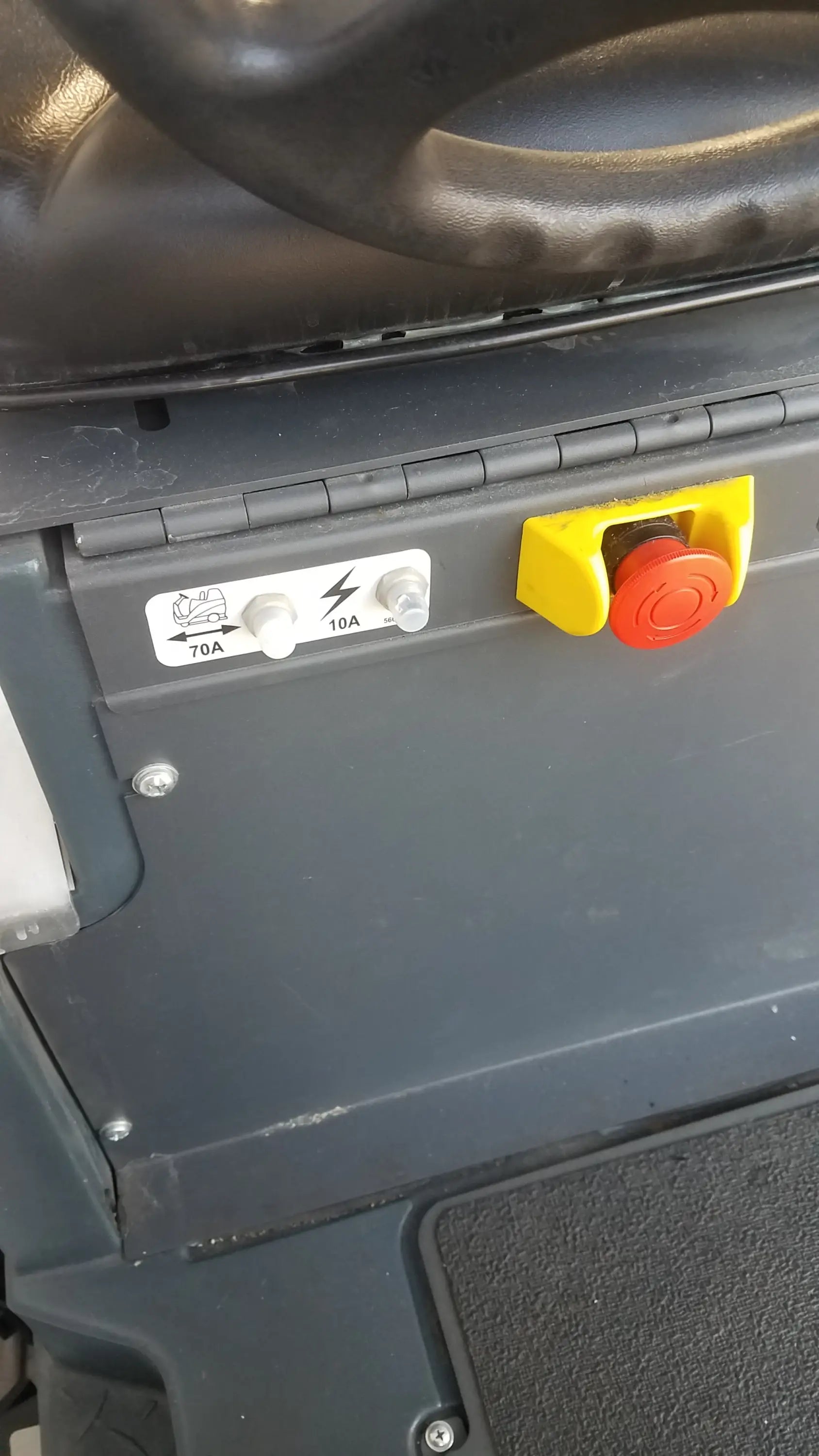 Yellow and red emergency stop button on dark gray panel of advance ride on carpet cleaner extractor wet dry vacuum