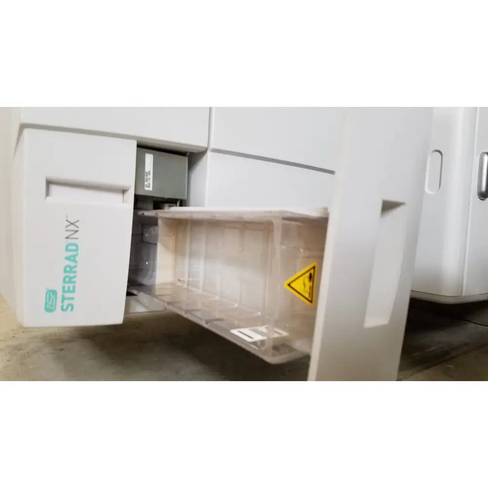 White advanced sterilization products sterrad nx sterilizer with transparent plastic tray and yellow warning label visible on side