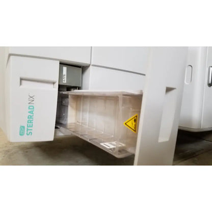 White advanced sterilization products sterrad nx sterilizer with transparent plastic tray and yellow warning label visible on side