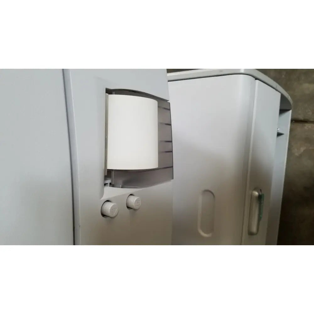 White cylindrical paper roll mounted in gray plastic dispenser with knobs for advanced sterilization products sterrad nx sterilizer