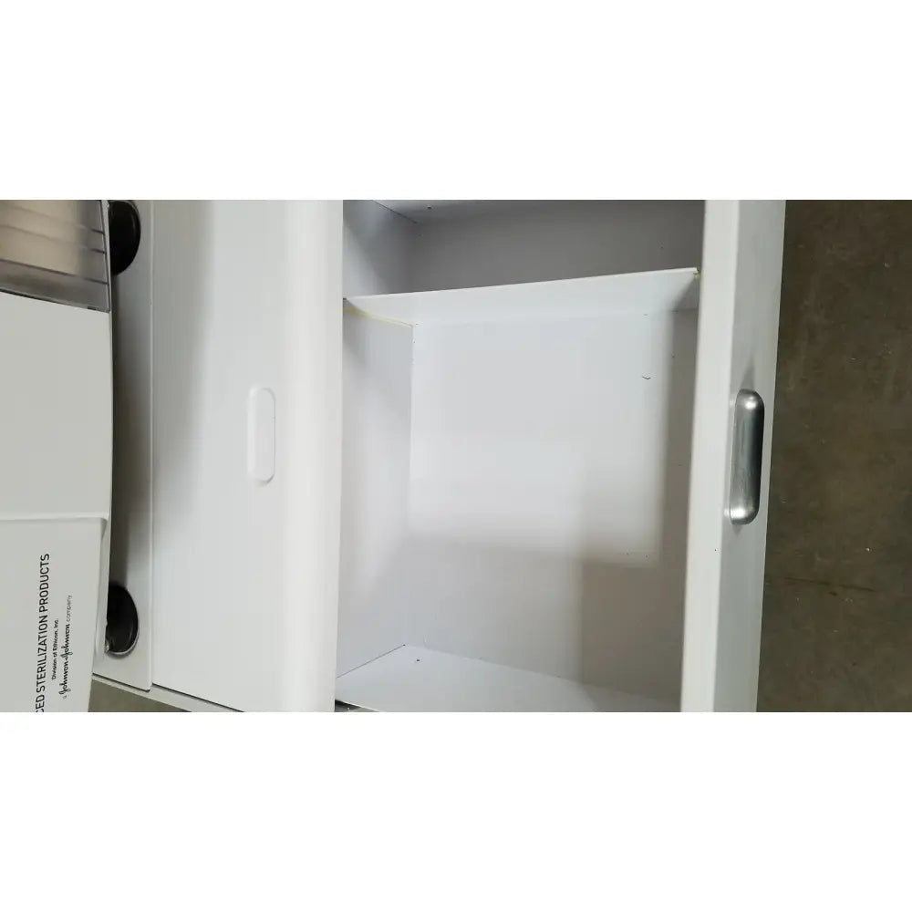 White cabinet of advanced sterilization products sterrad nx sterilizer with silver handle and black circular accents on the side