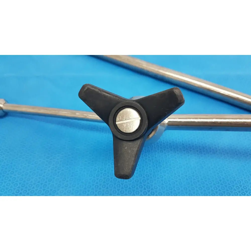 Black three-pronged knob with silver screw on metallic rods of aesculap ff168r surgical retractor system component