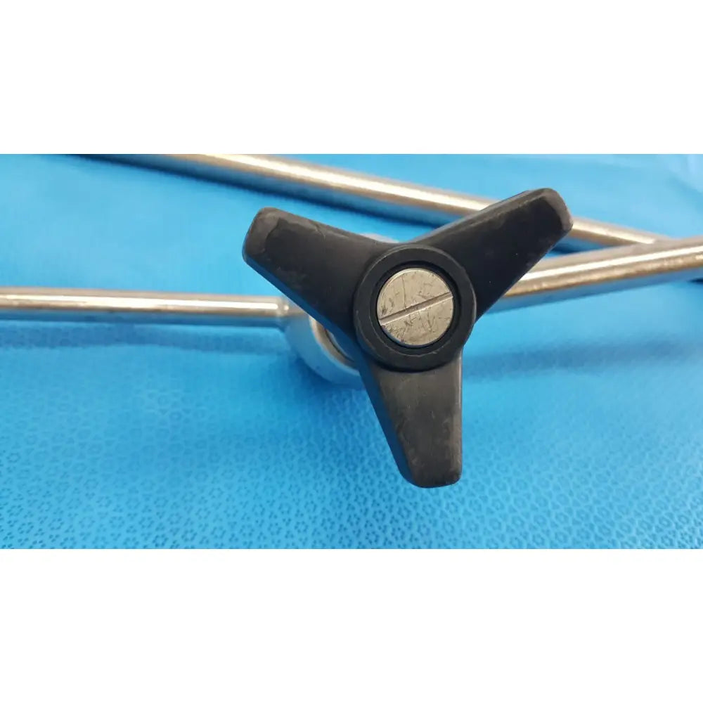 Black three-pronged knob with silver metallic center on metal rods for aesculap ff168r surgical retractor system component