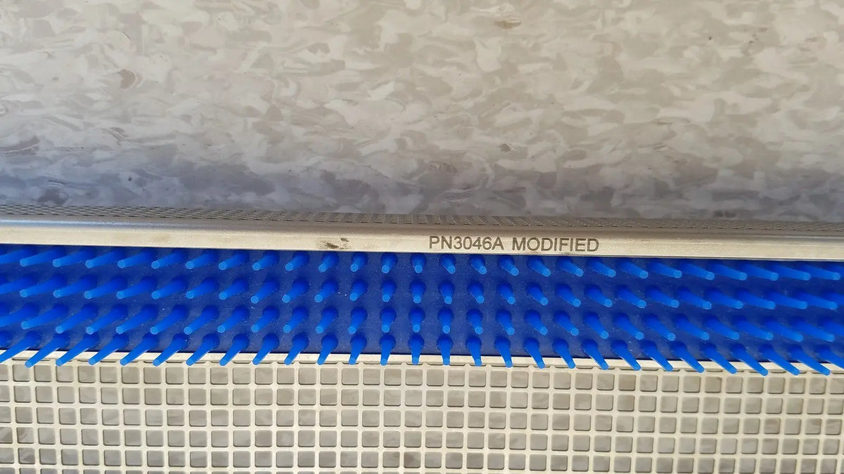Blue plastic comb-like component with white metallic frame marked pn3046a modified for aesculap jf257r sterilization case tray
