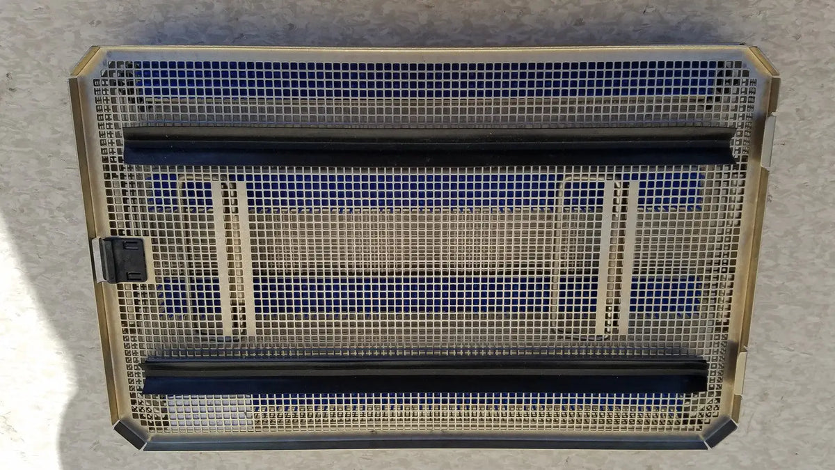 Rectangular metal mesh heater with gold-toned frame black heating elements and blue insulation panels in aesculap jf257r sterilization case tray