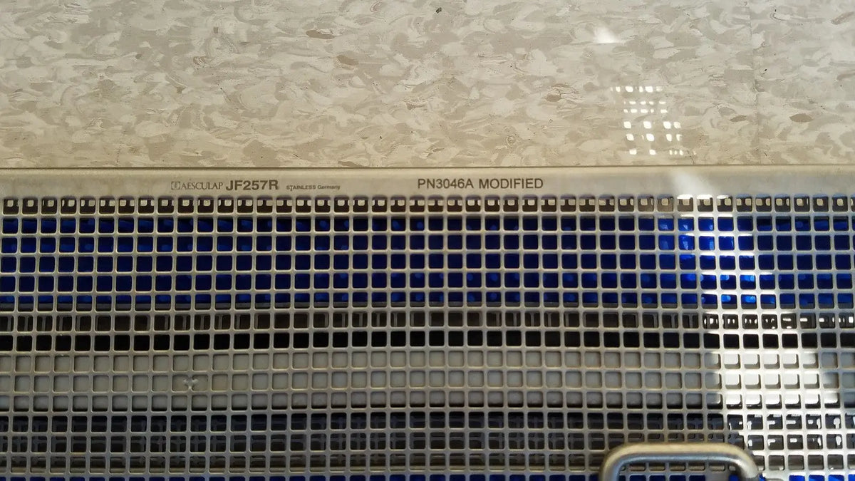 Stainless steel ventilation grille with engraved model markings on the back of aesculap jf257r sterilization case tray