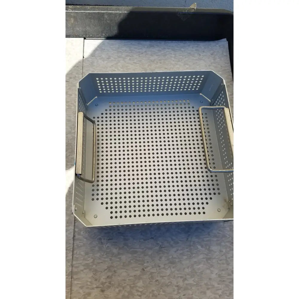 Gray perforated metal grill basket with two side handles for aesculap jk341 half size sterilization case and lid