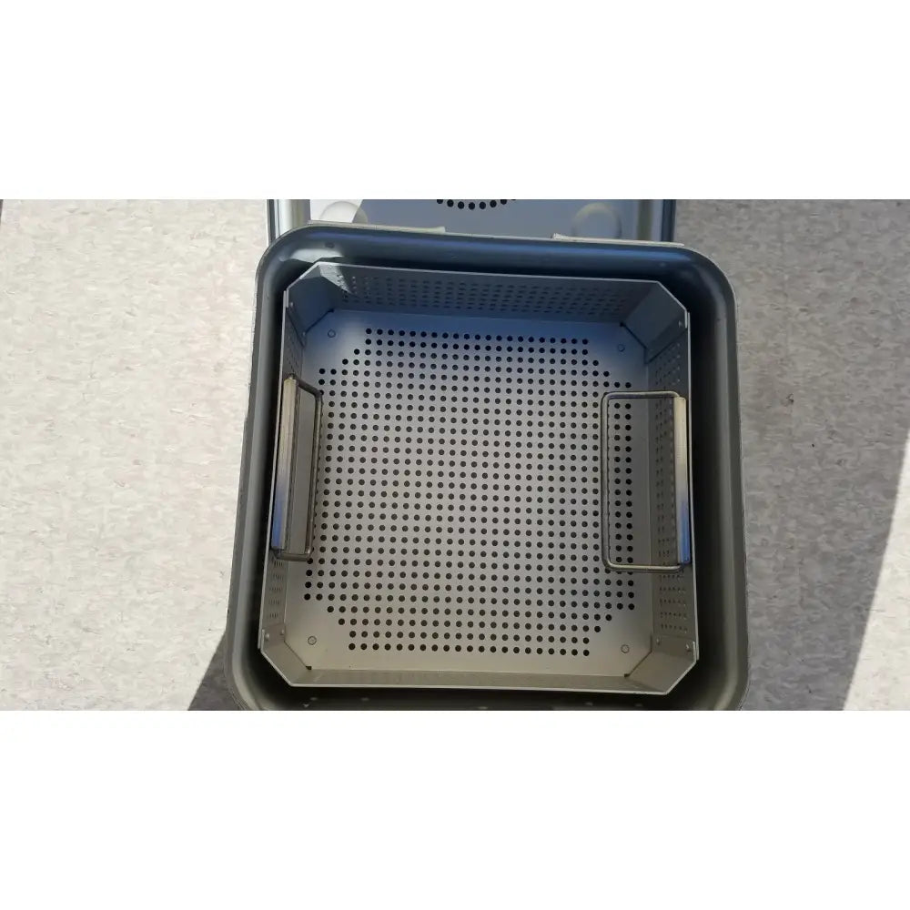 Gray perforated metal basket with two side handles in aesculap jk341 half size sterilization case with lid