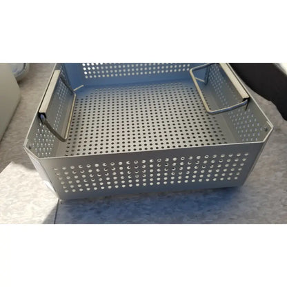 Gray perforated metal storage basket with reinforced side handles in aesculap jk341 half size sterilization case with lid