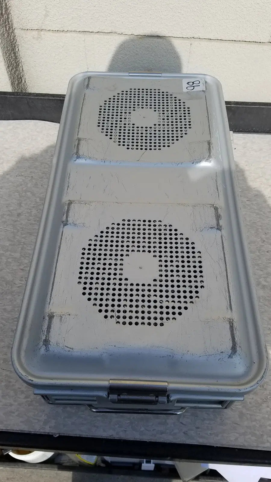 Gray plastic aesculap jk489 jk442 sterilization container case with two circular perforated panels and a metal latch