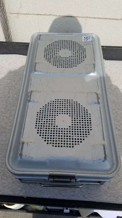 Gray plastic aesculap jk489 jk442 sterilization container case with two circular perforated panels and a metal latch