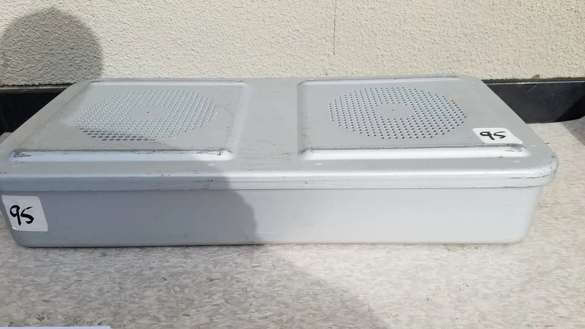 Gray plastic rectangular aesculap jn821 sterilization case with two perforated speaker grilles on the top surface