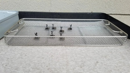 Silver mesh aesculap jn821 sterilization case instrument tray with black-handled clamps neatly arranged inside