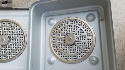 Silver metallic circular perforated grates set into a metal tray of the aesculap jn821 sterilization case instrument tray