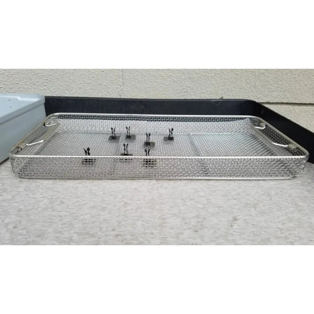 Silver mesh aesculap jn821 sterilization case instrument tray with black-handled clamps neatly arranged inside
