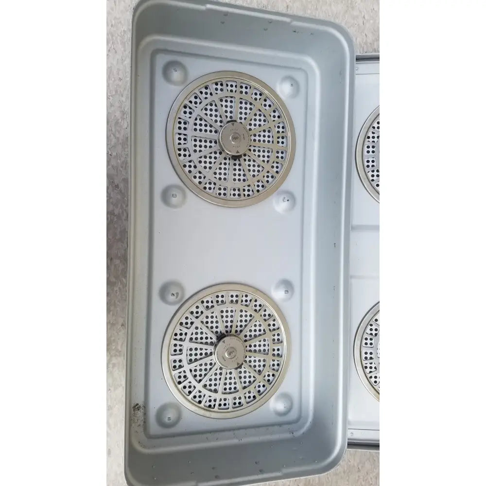 Silver metal grates with circular perforations and bolts inside an aesculap jn821 sterilization case instrument tray