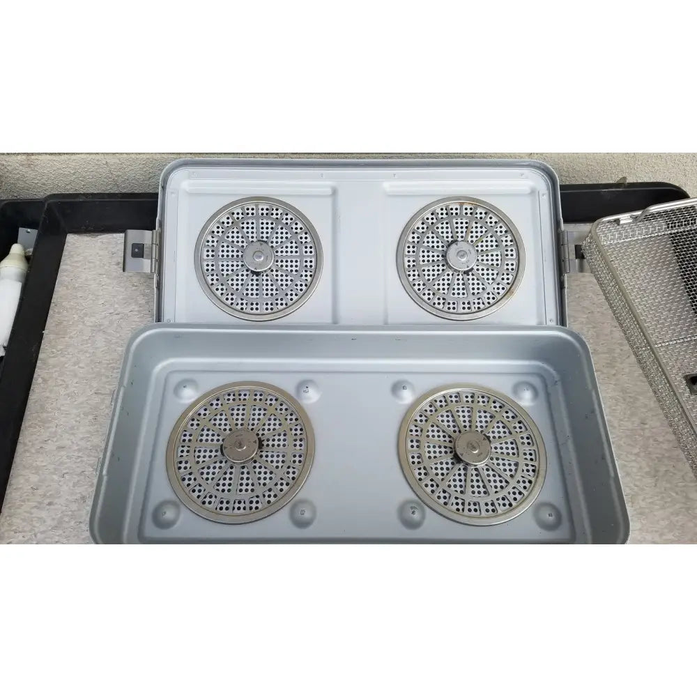 Silver-colored metal aesculap jn821 sterilization case instrument tray with four circular perforated heating elements in 2x2 grid