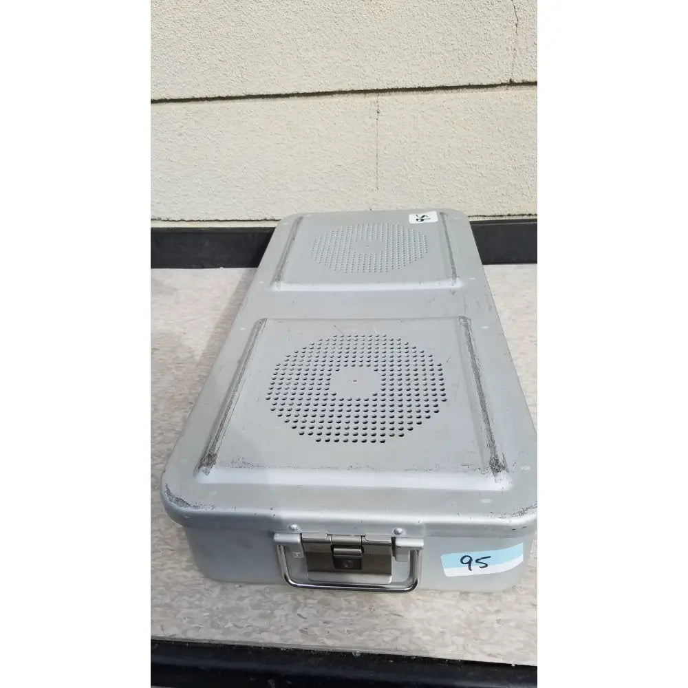 Gray metal aesculap jn821 sterilization case with two circular perforated speaker grilles and handle on top surface