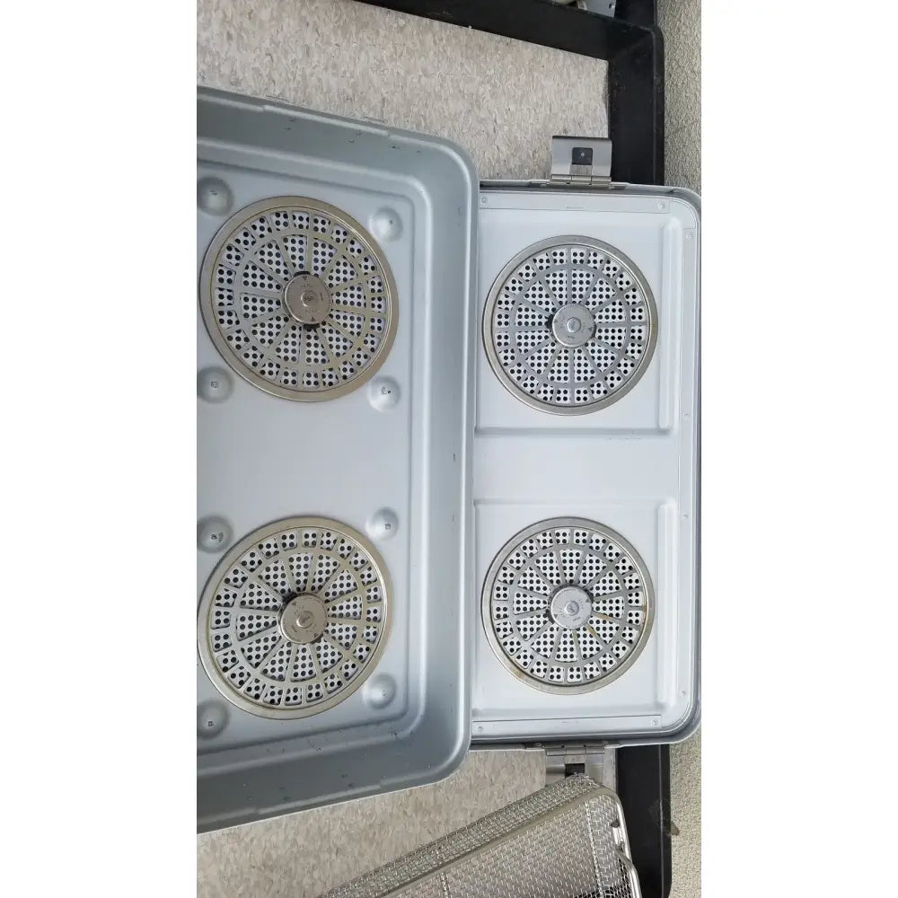 Gray plastic aesculap jn821 sterilization case with four circular metal mesh inserts and central bolts for instrument tray use