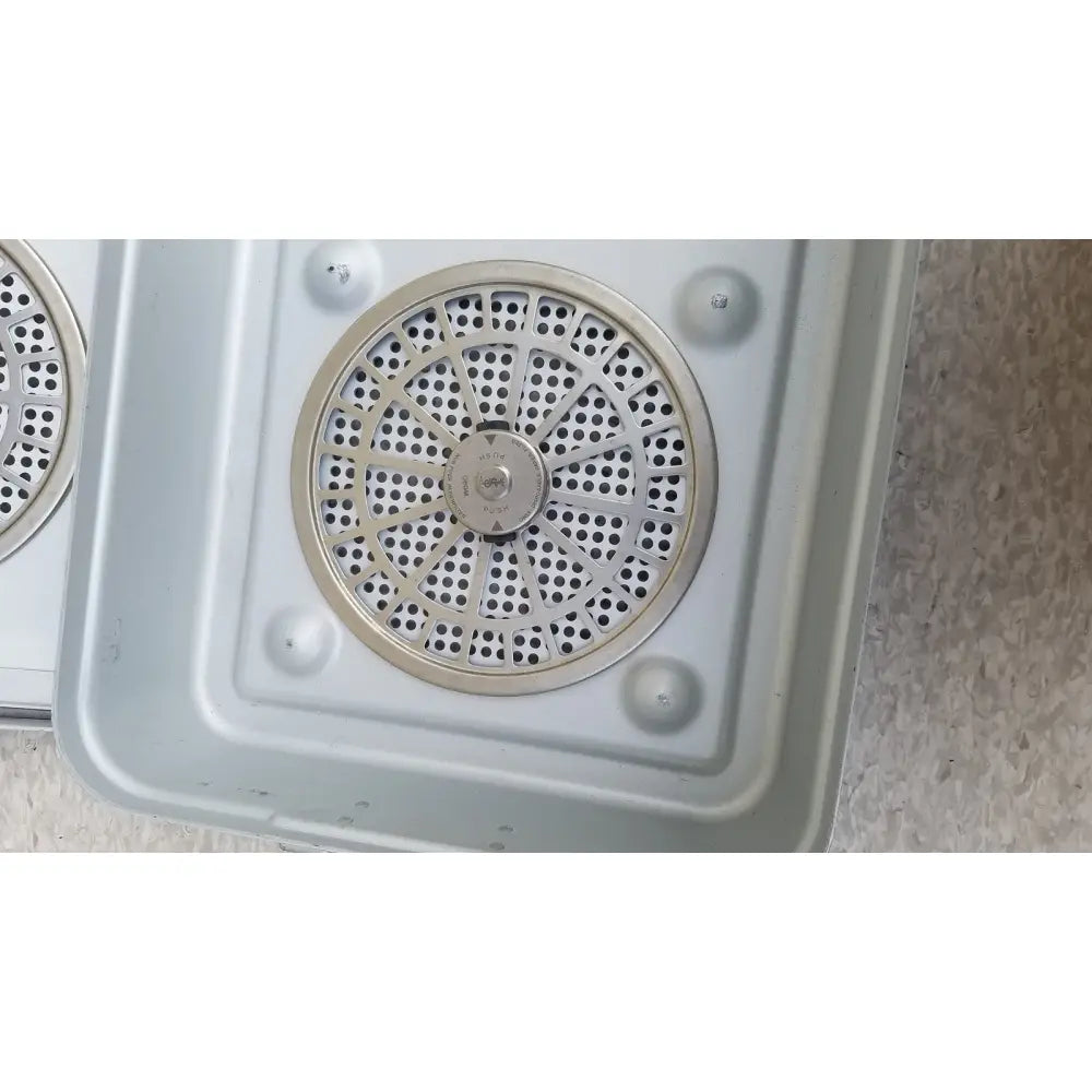 Silver circular vent with perforated metal grille and central control knob on aesculap jn821 sterilization case instrument tray
