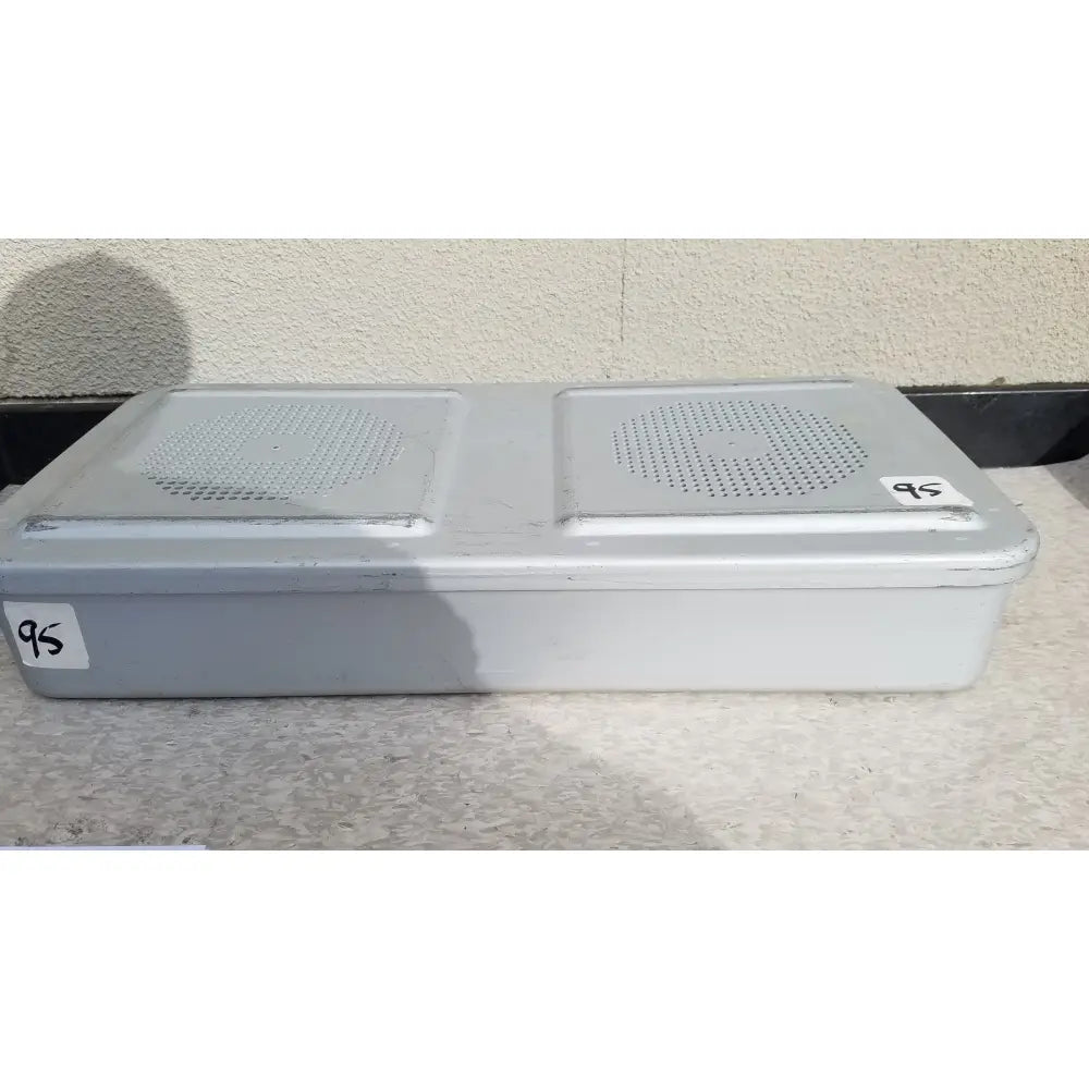 Gray plastic rectangular aesculap jn821 sterilization case with two perforated speaker grilles on the top surface