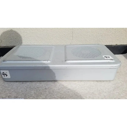 Gray plastic rectangular aesculap jn821 sterilization case with two perforated speaker grilles on the top surface