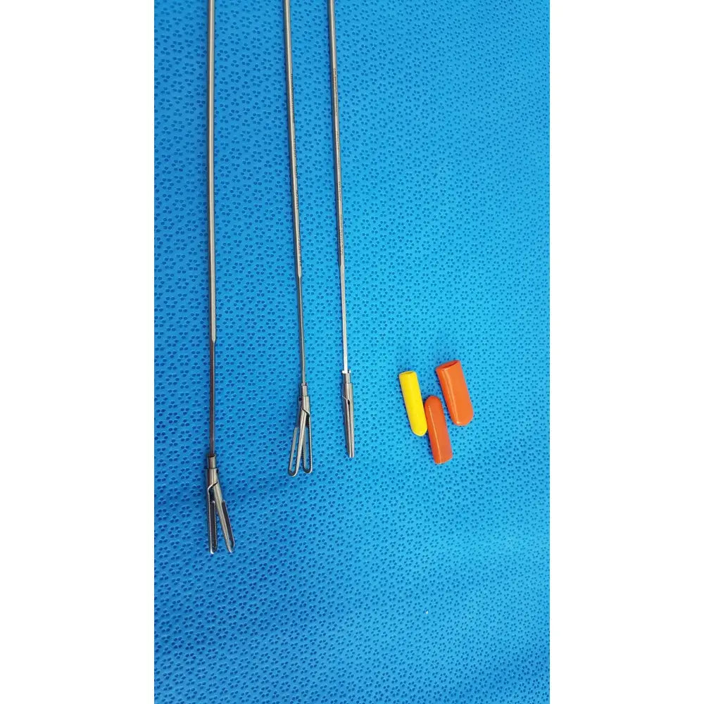 Three metallic aesculap laparoscopic instruments model 33310 with distinct tips and yellow and orange plastic caps for reuse medical use