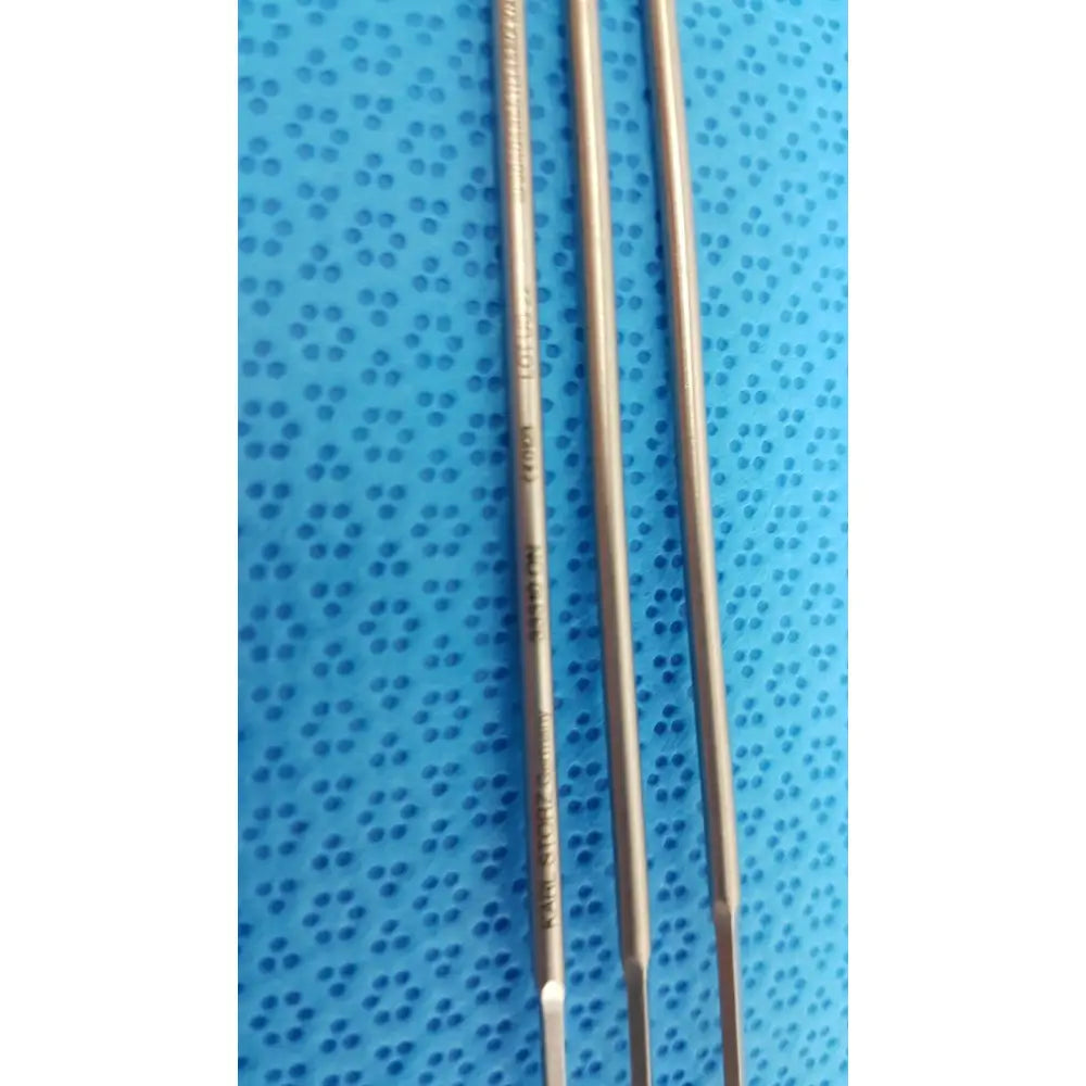 Three metallic aesculap laparoscopic instrument drill bits with engraved markings on a blue perforated surface