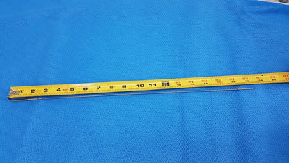 Yellow measuring tape with black markings and metallic end on blue surface beside aesculap pm618r laparoscopic instrument