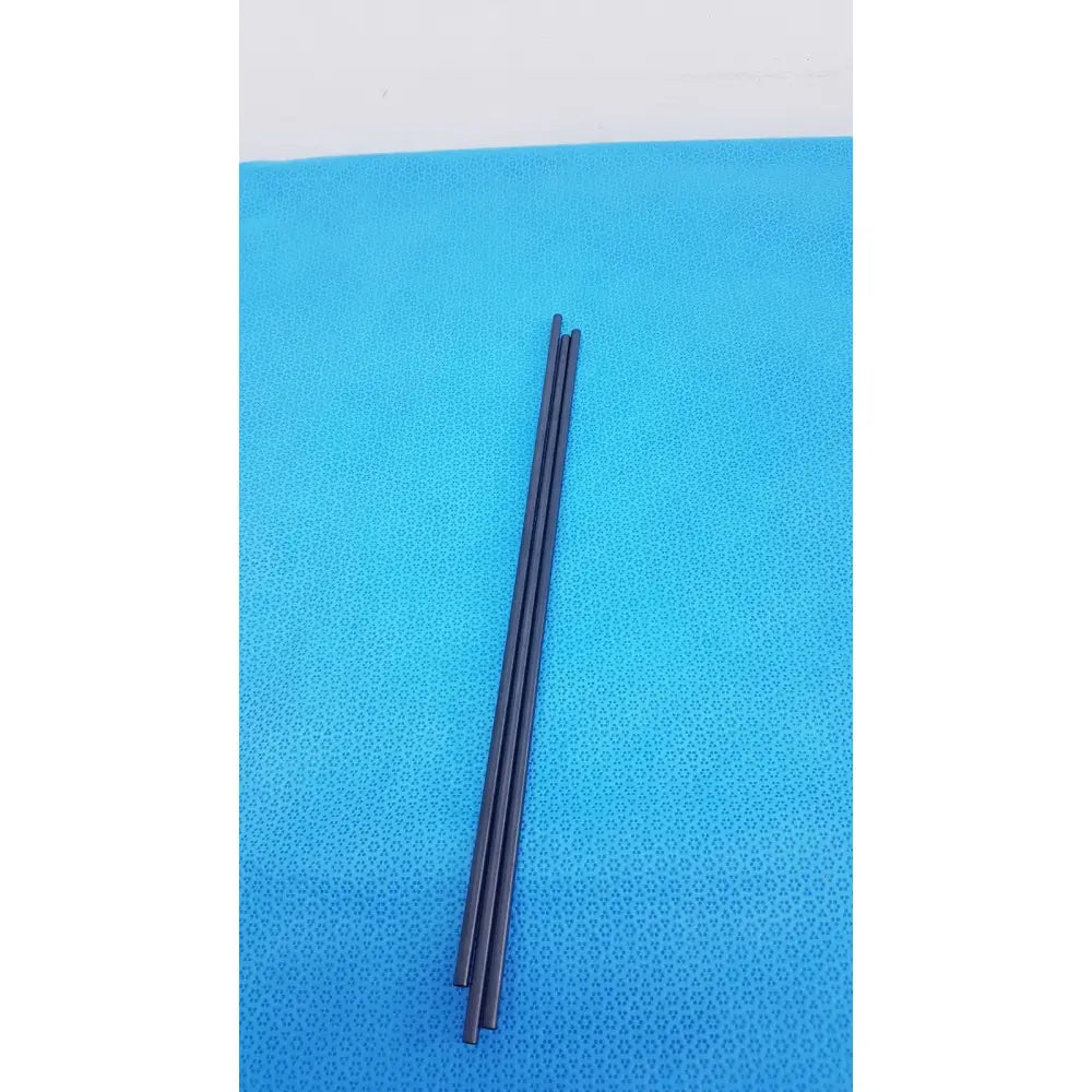 Three slender black aesculap pm973r insulated outer tubes 5 x 310 mm lie parallel on a textured blue surface
