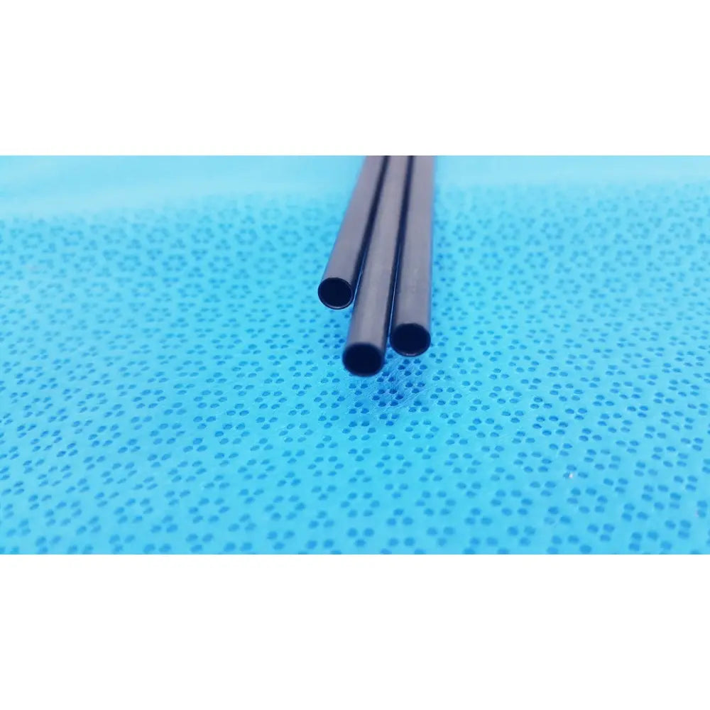 Three black pm973r insulated outer tubes 5 x 310 mm lie parallel on a perforated blue surface by aesculap